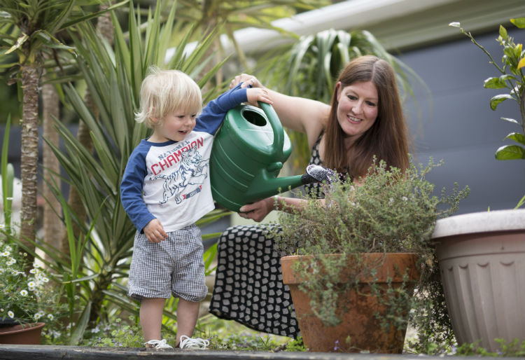 A family using a watering can to water the garden as part of their waterwise approach